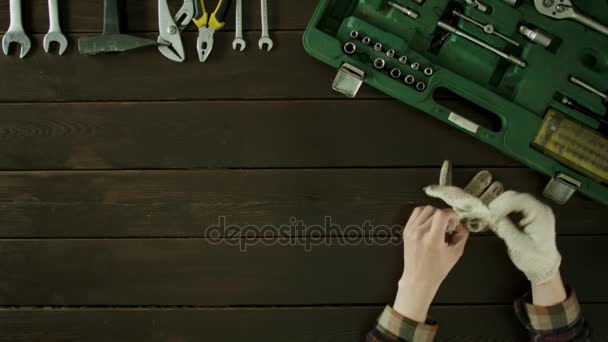 A man sits at a table and pulls tools out of a suitcase. — Stock Video