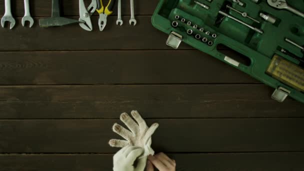 Een man zit aan een tafel in de buurt van de werkset en zet op de handschoenen en verwijdert ze. — Stockvideo