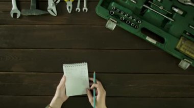 Araç kutusu ve Notepad ile yazılı çekleri yakınındaki bir masada bir adam oturuyor