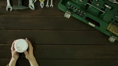 Bir adam oturur bir masa onun yanında bir bavul ve kahve içiyor.