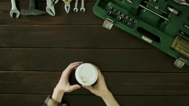 Un uomo seduto a un tavolo accanto a lui è una valigia e beve caffè . — Video Stock