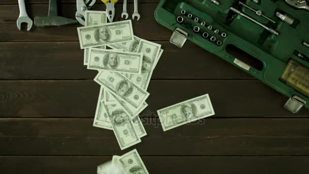 Un hombre se sienta en una mesa cerca de las herramientas son y recoge el dinero disperso . — Vídeo de stock