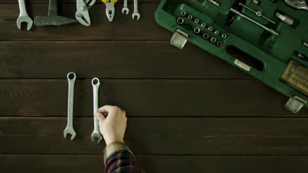En man sitter vid ett bord nära verktygen är och lägger ut skruvnycklar i storlek och fälls tillbaka. — Stockvideo