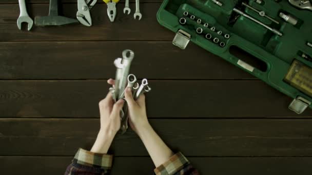 A man sits at a table near the tools are and lays out the spanners in size and folds back. — Stock Video