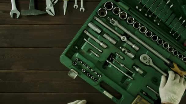 A man sits at a table and pulls tools out of a suitcase. — Stock Video