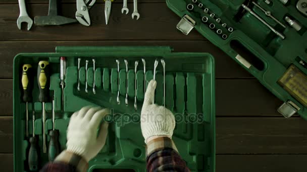 A man sits at a table and pulls tools in place of a suitcase. — Stock Video