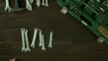 Bir adam araçları yakınındaki bir masada oturuyor ve somun anahtarları boyutunda ortaya konuyor ve geri pas geçiyor.