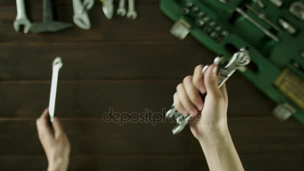 Un uomo si siede a un tavolo vicino agli strumenti sono e dispone le chiavi in dimensioni e si piega indietro . — Video Stock