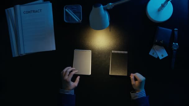 Un hombre mira a través de sus cuadernos y elige el gris . — Vídeos de Stock