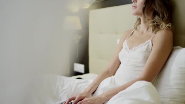 Радісна жінка працює на ноутбуці вранці на ліжку — стокове відео