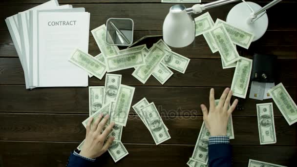 El dinero está esparcido por toda la mesa de la oficina y el hombre los recoge. . — Vídeo de stock