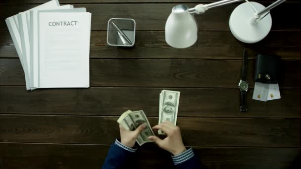 Un hombre se sienta en la mesa de la oficina, y cuenta el dinero . — Vídeos de Stock