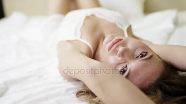 Mulher sonolenta deita-se na cama de costas e posando — Vídeo de Stock