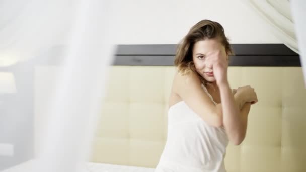 Örömteli nő pózol a póló fehér hálóruha ágy — Stock videók