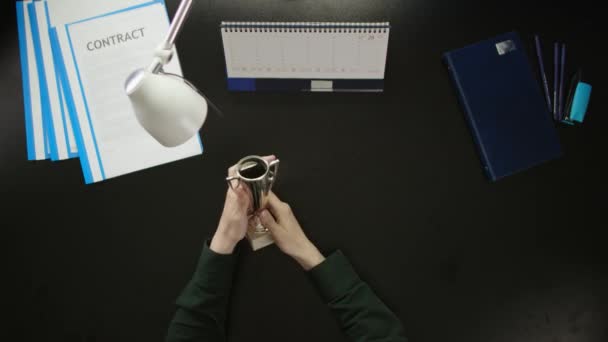 Een man is aan een bureau zitten en met behulp van een telefoon. — Stockvideo