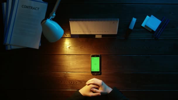 Um homem está sentado em uma mesa de escritório e usando um telefone . — Vídeo de Stock