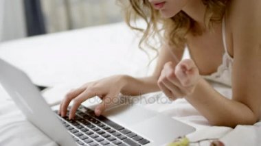 Kadın onun laptop ve kredi kartı kullanarak yatağında bir şey online satın alma