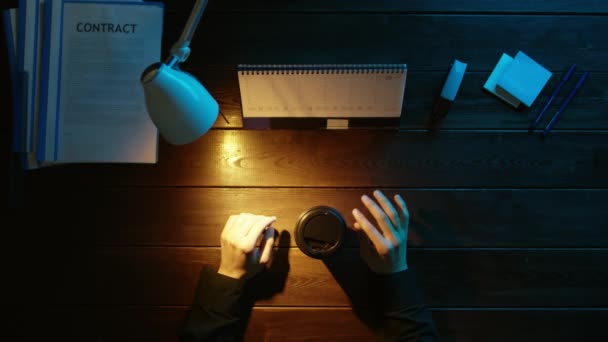 Un homme est assis à un bureau et utilise un téléphone . — Video