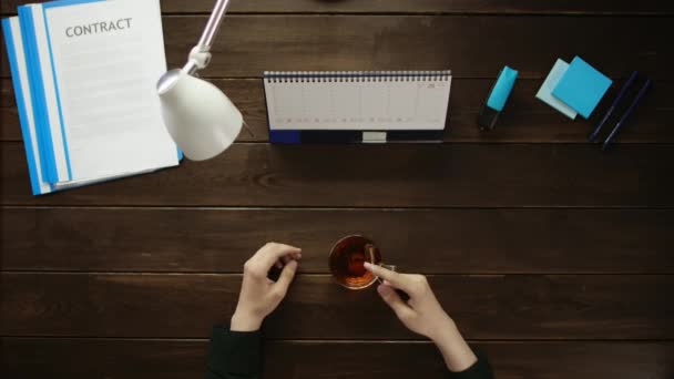 Een man is aan een bureau zitten en met behulp van een telefoon. — Stockvideo