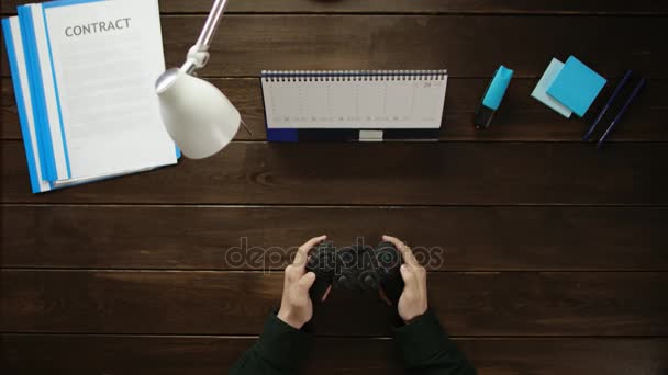 Een man is aan een bureau zitten en met behulp van een telefoon. — Stockvideo