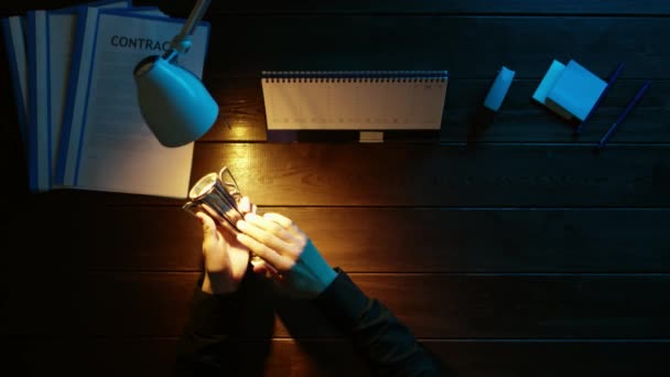 Een man is aan een bureau zitten en met behulp van een telefoon. — Stockvideo