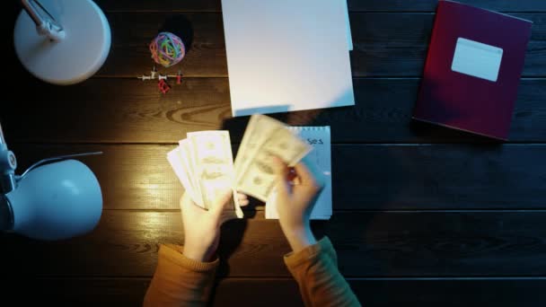 El hombre en el escritorio pegamento stikers en el cuaderno y contar el dinero, junto a la carpeta, lámpara, bola, oficina y botones . — Vídeo de stock