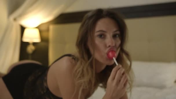 Aantrekkelijke vrouw hard candy zuigen op bed — Stockvideo