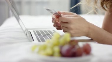 Yatak ve onun laptop ve kredi kartı kullanarak alışveriş online üzerinde pijama yalan tatlı kadın giyinmiş