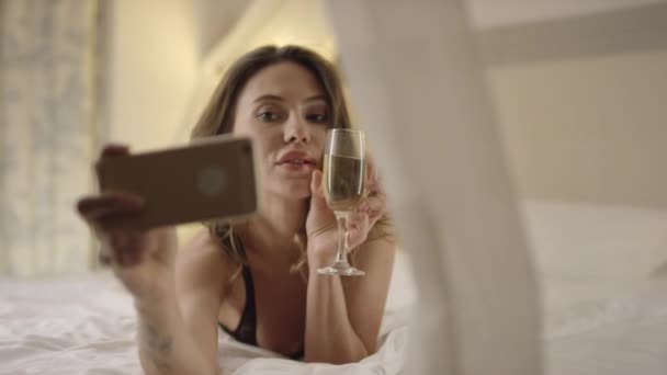 Zarte Frau trinkt Weißwein und macht Selfshot im Bett — Stockvideo