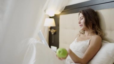 Çekici kadın kadar bir yeşil elma savurma yatağa Tablet PC'yi kullanma