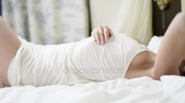 Güzel kadın yatakta poz ve kendini okşayarak beyaz pijama iç çamaşırı