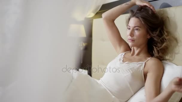 Mujer joven hablando por teléfono celular mientras está acostada en la cama con un vaso de vino tinto — Vídeos de Stock