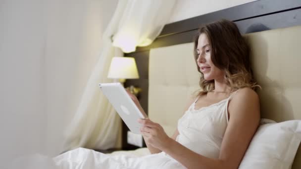 Vrouw die tablet pc gebruikt op bed — Stockvideo