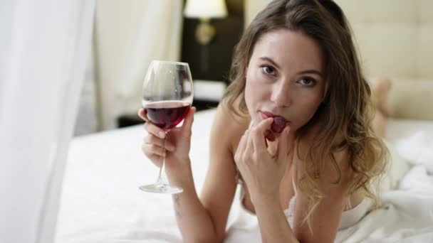 Mulher bebe vinho tinto e come uva na cama — Vídeo de Stock