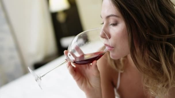 ゴージャスな女性がワインを飲むし、ベッドの上のブドウを食べる — ストック動画
