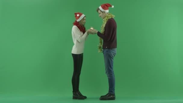 Casal jovem sopra vela de Natal junto com a tecla chroma no fundo — Vídeo de Stock