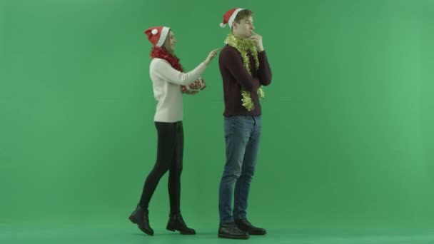 Jovem mulher dá ao namorado um presente de Natal muito agradável e ele a abraça com a chave chroma no fundo — Vídeo de Stock