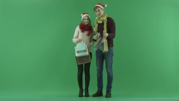 Junges Paar zeigt Kreditkarte in die Kamera, während es Einkaufstüten hält, Chroma-Schlüssel im Hintergrund — Stockvideo