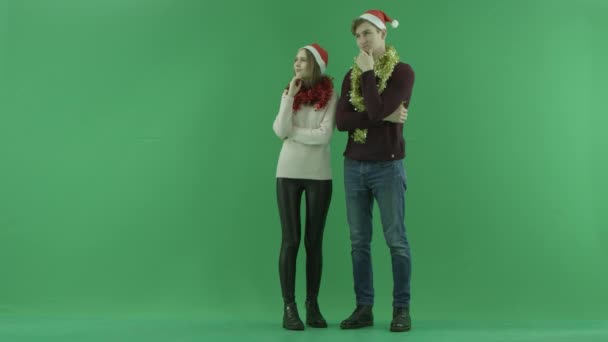 若いカップルはクリスマスイブ、背景にクロマキーで何かと考えています。 — ストック動画