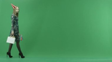 Kap içinde çekici genç kadın ile alışveriş torbaları, chroma anahtar arka plan üzerinde yürür.