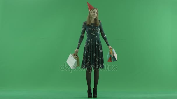 Frumoasă femeie tânără în capac cu saci de cumpărături, cheie de cromă pe fundal — Videoclip de stoc