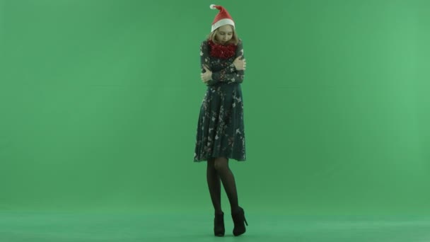 Young attractive woman in Christmas hat freezes and tries to keep warm, chroma key on background — Stock Video