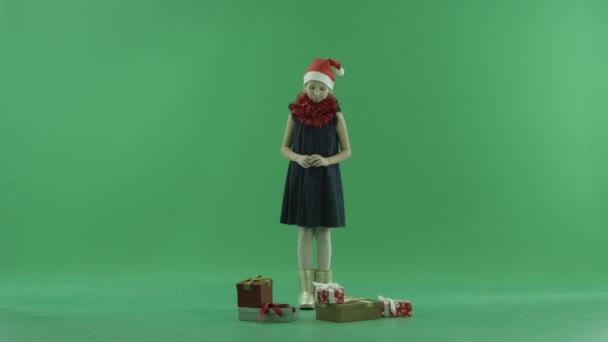 Dziewczynka w Santa hat unosi się świąteczny prezent z podłogi, Kluczowanie na tle — Wideo stockowe