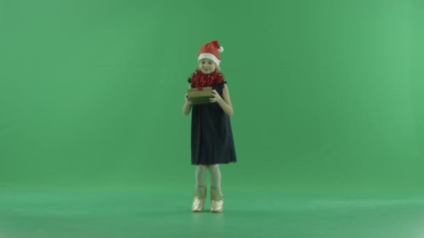 Симпатична маленька дівчинка в різдвяному капелюсі отримала гарний подарунок Різдва, ключ від хрому на фоні — стокове відео