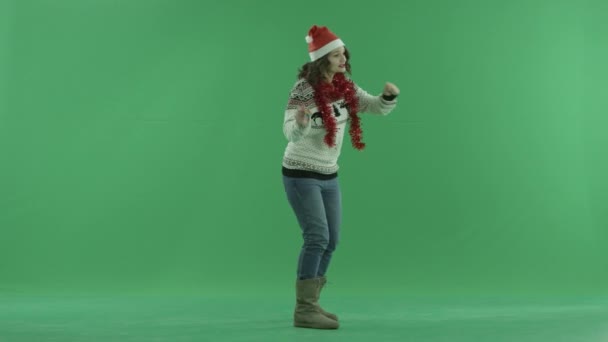 Charming woman in Christmas hat dances and blows in whistle, chroma key on background — Stock Video