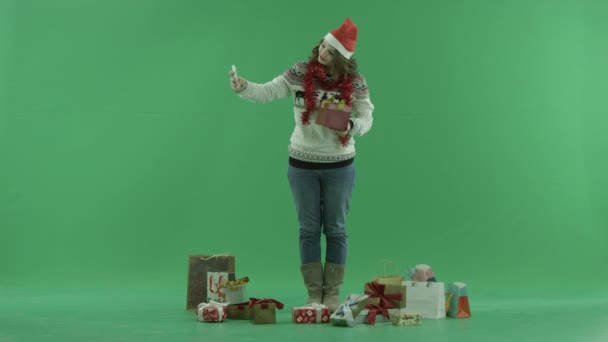 Attraktiv ung kvinna i jul hatt tar foto av julklapp, Färgtransparens på bakgrund — Stockvideo