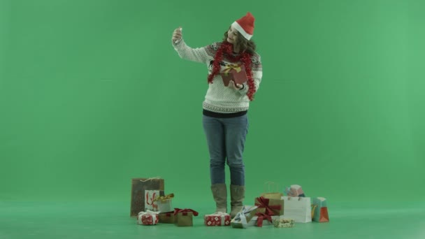 Attractive young woman in Christmas hat takes selfie with Christmas present, chroma key on background — Stock Video