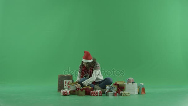 Attraente giovane donna in cappello di Natale ottenuto vuoto scatola regalo di Natale, chiave cromatica su sfondo — Video Stock