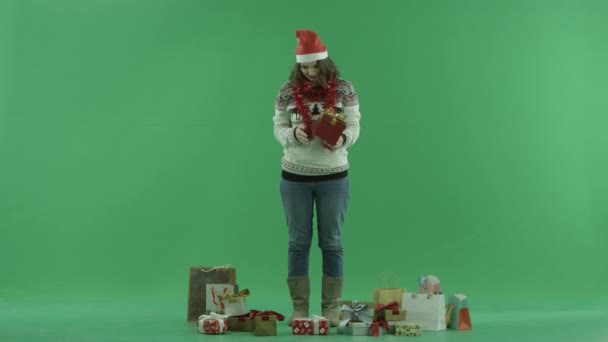 Karácsonyi kalapban nézi őt Xmas jelen, chroma key, a háttérben a gyönyörű fiatal nő — Stock videók