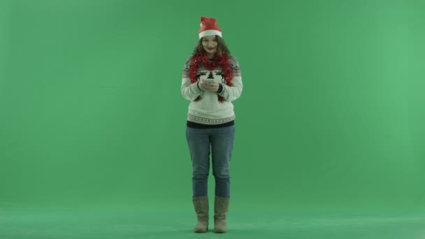 Joyeux jeune femme en chapeau de Noël avec smartphone, clé chromatique sur fond — Video